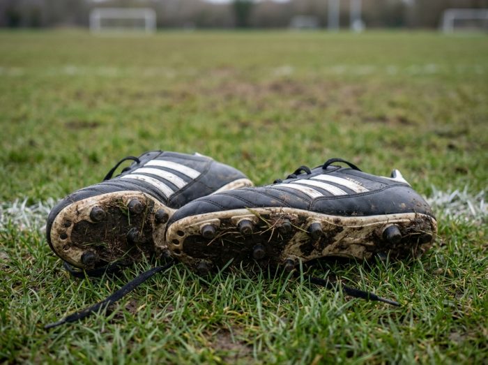 Gros plan sur une paire de crampons Adidas posée sur le gazon humide après un entraînement de football
