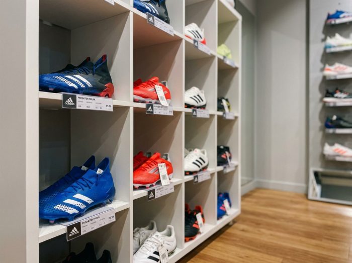 Rangée de crampons de football Adidas en différents modèles exposés dans un magasin de sport